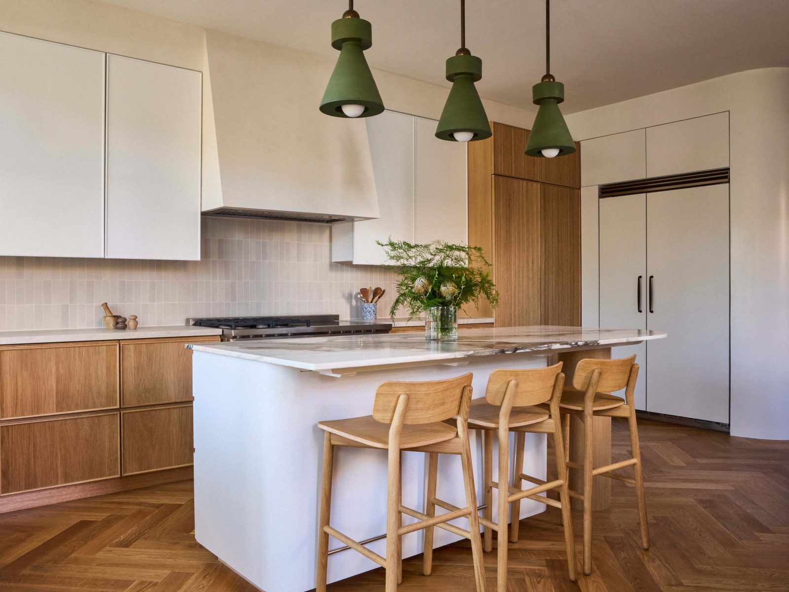 An airy kitchen incorporates generous storage and sculptural lighting, creating a distinctive locus for cooking and socializing.