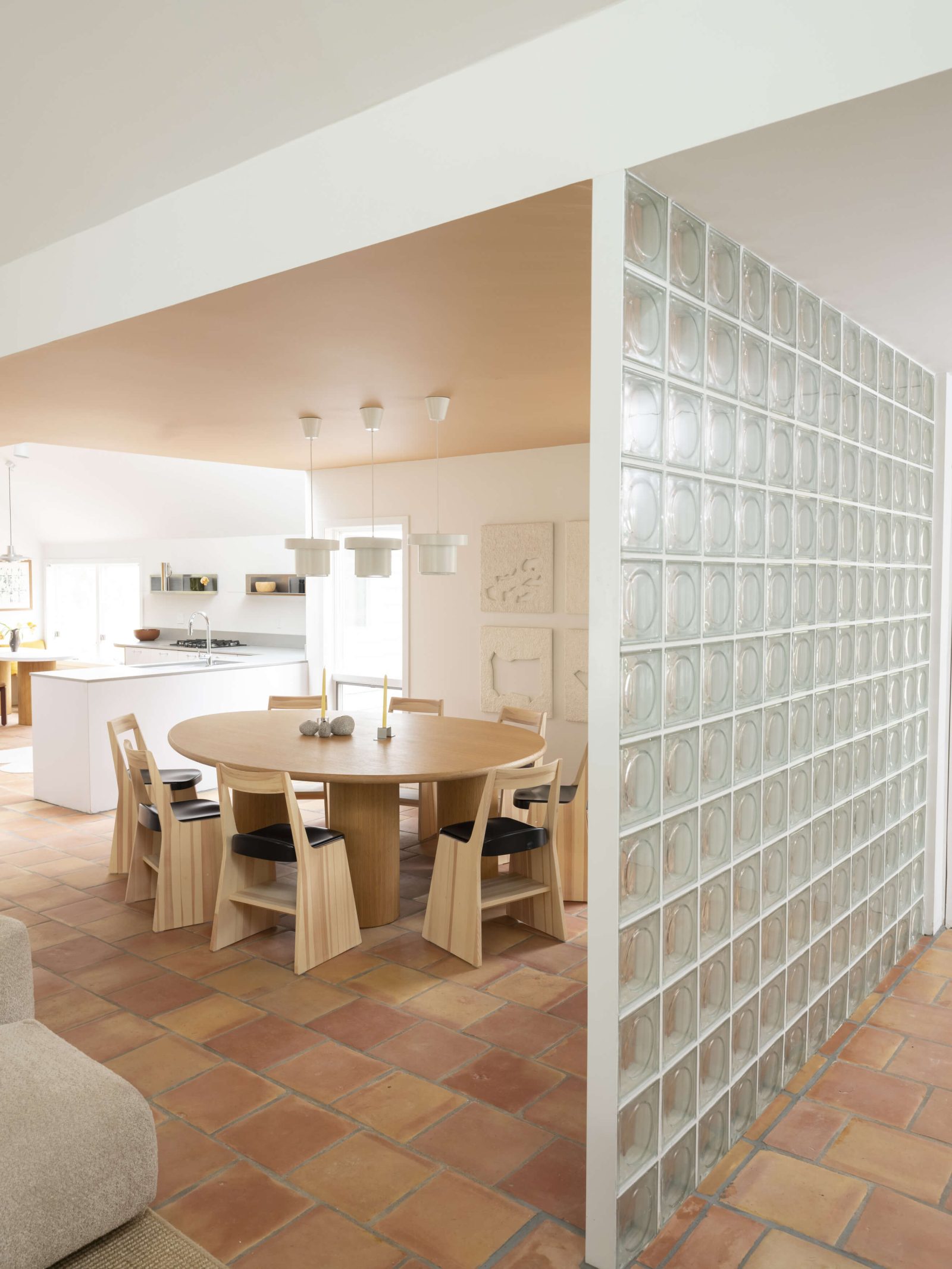 The glass-block partition flanks the dining room and its adjoining kitchen and breakfast nook&mdash;all united through a terra-cotta floor.